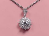 a diamond flower pendant on a chain on a pink background
