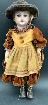 une petite poupée qui porte un chapeau et une robe