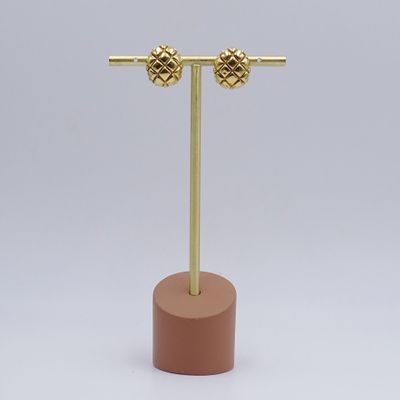 une paire de boucles d'oreilles plaquées or posées sur un support en bois