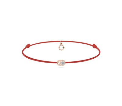 un bracelet en cordon rouge orné d'une breloque en forme de cœur et d'un diamant