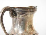 a silver pitcher sitting on a table with a white background
