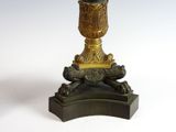 a gold vase on top of a black base on a white background