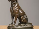 statue en bronze représentant un chien assis sur un socle en bois