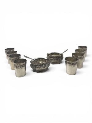 several silver cups with spoons and spoon rest on a white surface