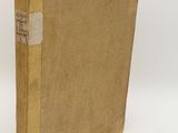 an old book sitting on top of a white table next to a white wall