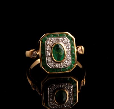 gros plan d'une bague en or avec une pierre verte et des diamants