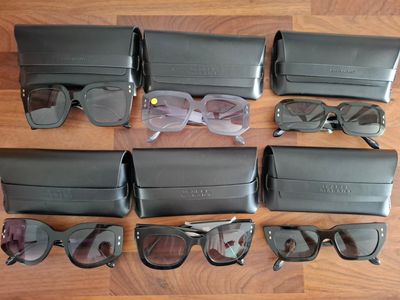 plusieurs paires de lunettes de soleil et un étui posés sur un plancher en bois