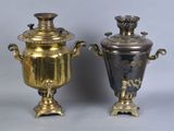 pair of antique brass urns on pedestals on grey background