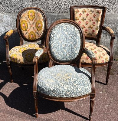 three chairs with floral upholstered cushions sit in front of a wall