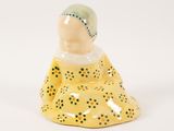 a small ceramic figurine of a woman sitting on the ground
