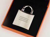 a silver padlock in a black box on a white surface