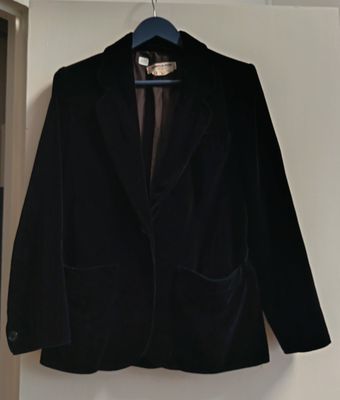 un blazer noir suspendu à un cintre dans une pièce blanche