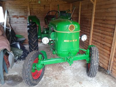 un tracteur vert garé dans un garage, avec d'autres tracteurs en arrière-plan