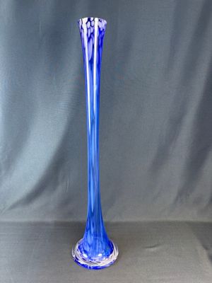 un vase en verre bleu posé sur une surface grise