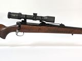 le fusil est posé sur un support transparent équipé d'une lunette de visée