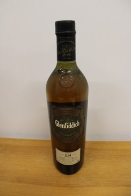 the bottle of whisky is sitting on the table next to the glass