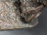 a bronze statue of a man sitting on a rock