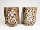 deux vases marron percés de trous, posés sur une surface blanche