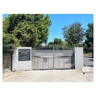 le portail d'entrée d'un parc sur lequel est accrochée une pancarte