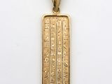 a gold plated pendant with an egyptian hierole on it