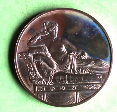 a silver coin with a statue on it on a green surface