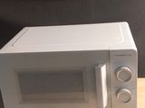 un micro-ondes posé sur une table en bois, sur fond noir