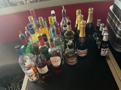 Des bouteilles d'alcool sont alignées sur une table à côté d'une valise