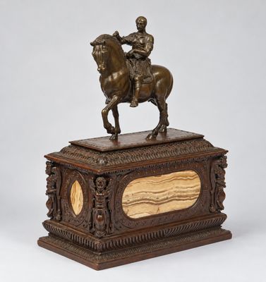 une statue en bronze représentant un homme à cheval, posée sur un socle en bois
