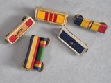 four different colored ribbons on a white surface with a gold clasp