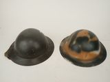 pair of wwii era german steel helmets on a white background