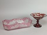 une paire de plats en verre roses et blancs et un saladier posé sur un socle