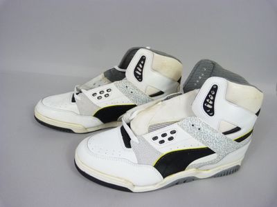 une paire de baskets blanches et noires avec des touches de noir sur une base grise
