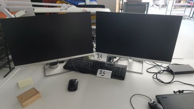 deux écrans d'ordinateur posés sur un bureau à côté d'un ordinateur portable