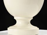 a white vase sitting on a table with a black background