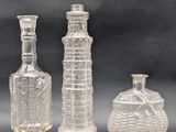 three clear glass vases and a glass bottle on a table