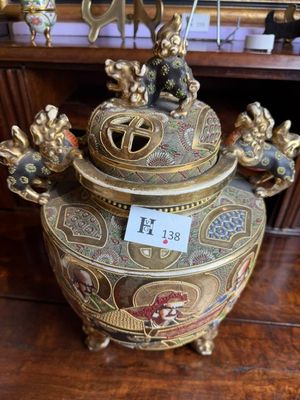 a gold and red vase on a table with a price tag