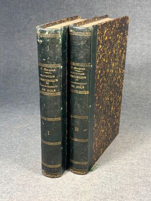 two old books sitting on top of each other on a table