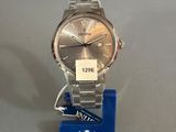 the watch is sitting on a stand with a blue tag attached to it