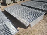 plusieurs grilles en acier sont empilées les unes sur les autres au sol
