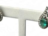 une photo d'une paire de boucles d'oreilles en émeraude et diamant posées sur un présentoir