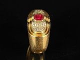a close up of a gold ring with a red stone in it