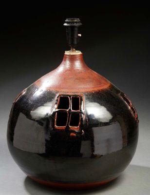 un vase noir et rouge avec un couvercle noir posé sur une table