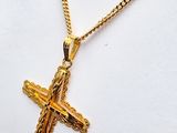a gold cross pendant with a chain on a white background