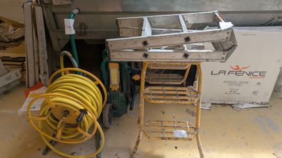 Les tuyaux jaunes se trouvent sur un chariot dans un garage, à côté d'une pile de cartons