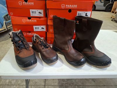 Trois paires de bottes marron et noires sont posées sur une table blanche