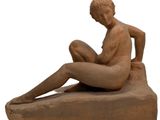 statue of a woman sitting on a rock with her legs crossed