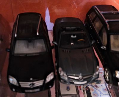 Plusieurs petites voitures sont alignées sur une étagère dans une vitrine.