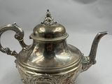 une théière en argent avec un couvercle, posée sur un socle