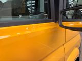 a side view mirror of a yellow bus parked in a parking lot