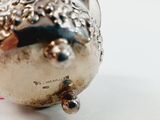 a small silver object on a white surface with a red flower